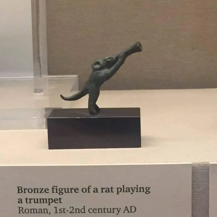 Bronze figure of a rat playing trumpet.